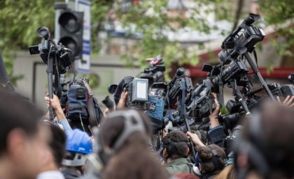 A large group of journalists and camera operators filming event. Image, Adobe. 